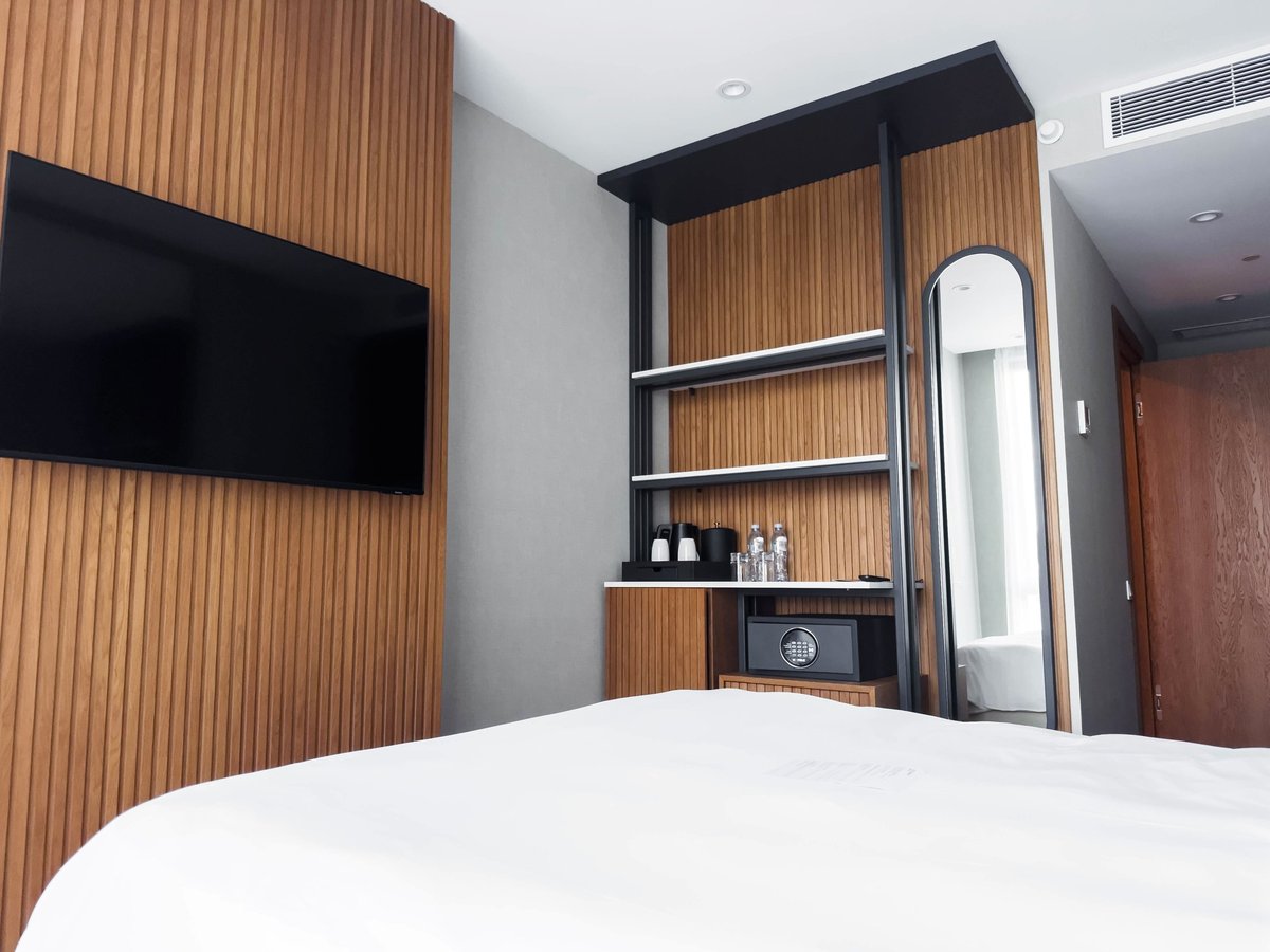 Midis Otel deluxe odası: ahşap kaplama, düz ekran TV, minibar ve açık raflar