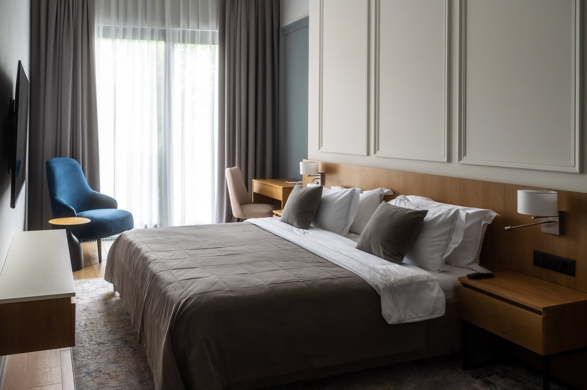 Midis Otel standart odası: konforlu yatak, ahşap başlık ve pencere kenarında mavi koltuk