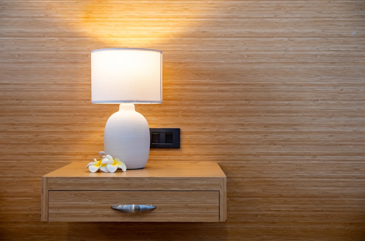 Warm table lamp and flowers on a wooden nightstand in a Midis Otel room